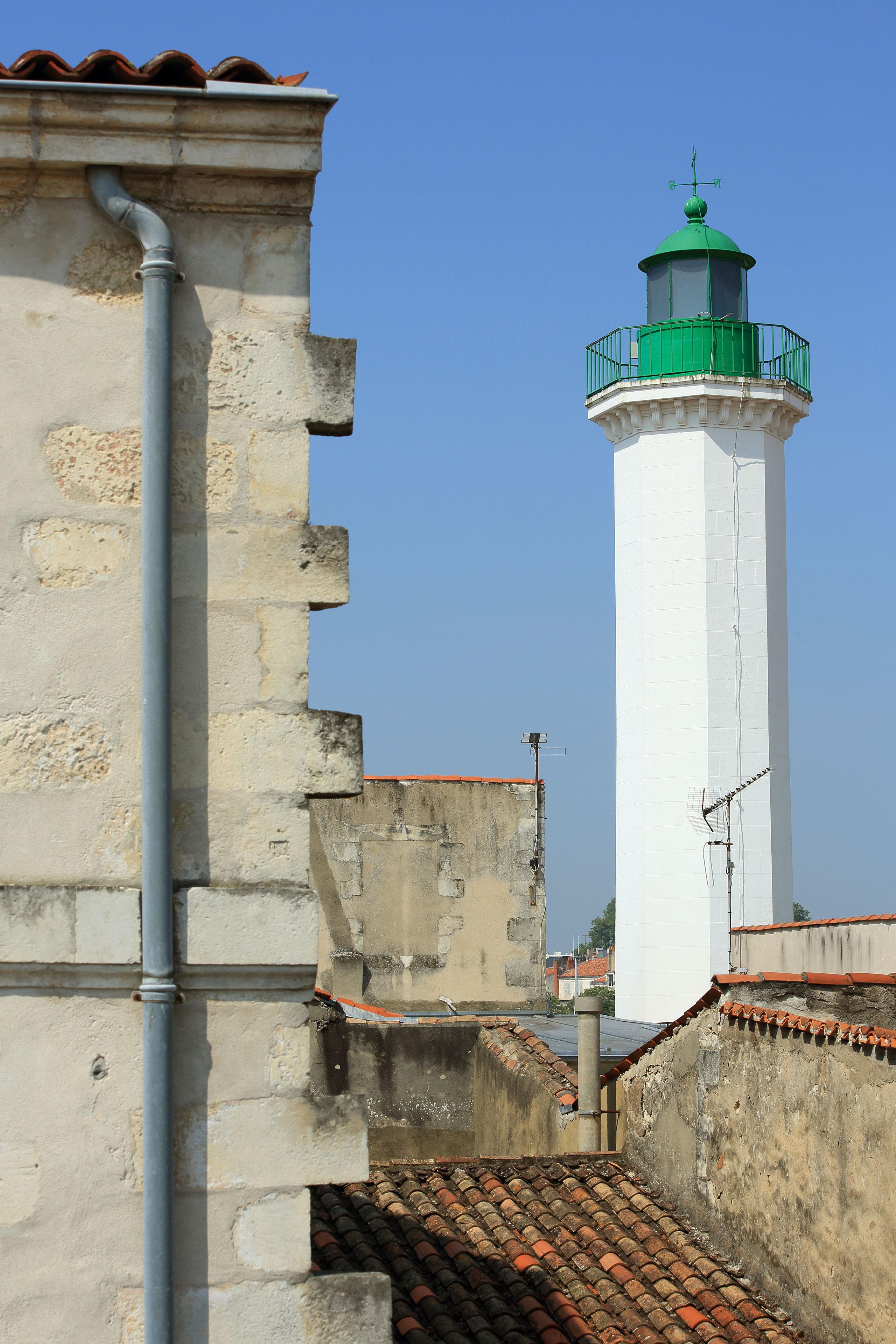 Ein Leuchtturm mit grüner Spitze, einem weißen zylindrischen Körper und einem roten Ziegeldach.