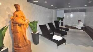 A spa area with a statue, black lounge chairs, and potted plants.