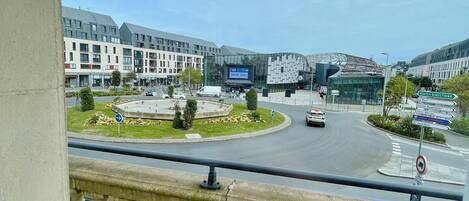 A modern building with a glass facade, a roundabout with a traffic island, and a clear sky.