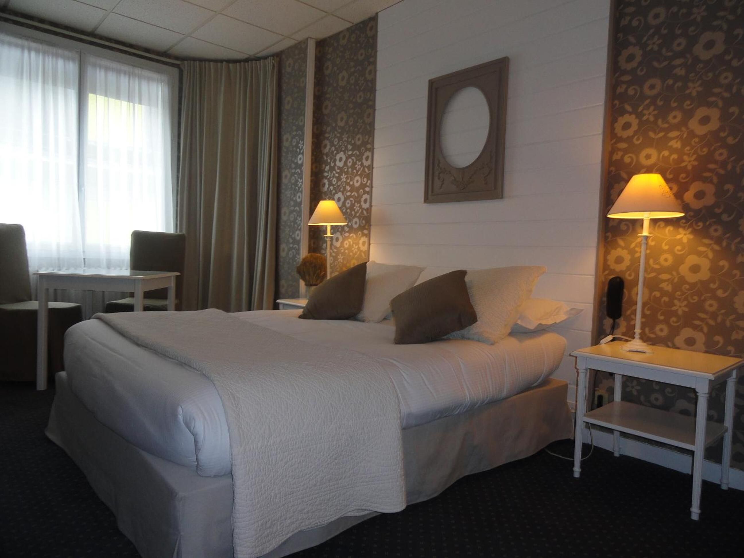 A hotel room with a large bed, two bedside tables with lamps, a desk, and a chair.