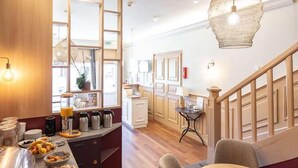Una cocina moderna con encimera de madera, una zona de comedor con una mesa redonda y sillas, y una escalera con barandillas de madera.