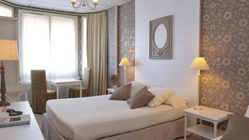 A hotel room with a bed, bedside tables, a desk, and a chair.