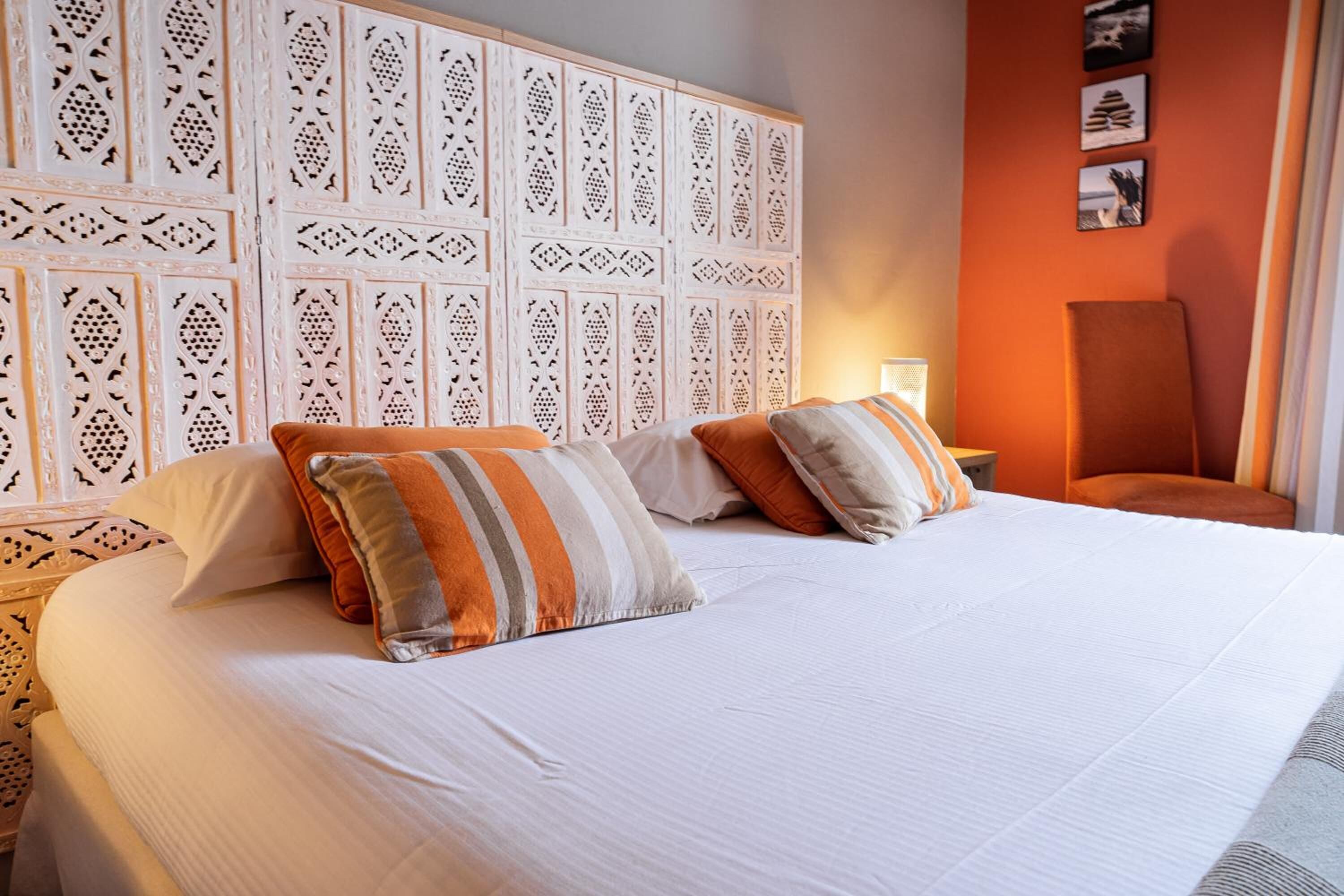 Habitació d'hotel amb un llit gran, un panell decoratiu al capçal i una cadira.