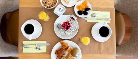 Una bandeja de desayuno con diversas opciones de comida y bebida, como cereal, pasteles y jugo de naranja.
