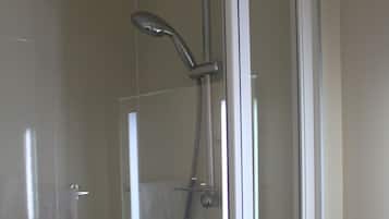 A glass-enclosed shower stall with a handheld showerhead and a handheld hose.