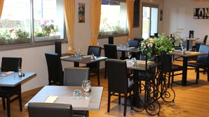 Un restaurante con mesas dispuestas para comer, sillas y un centro de mesa con planta decorativa.