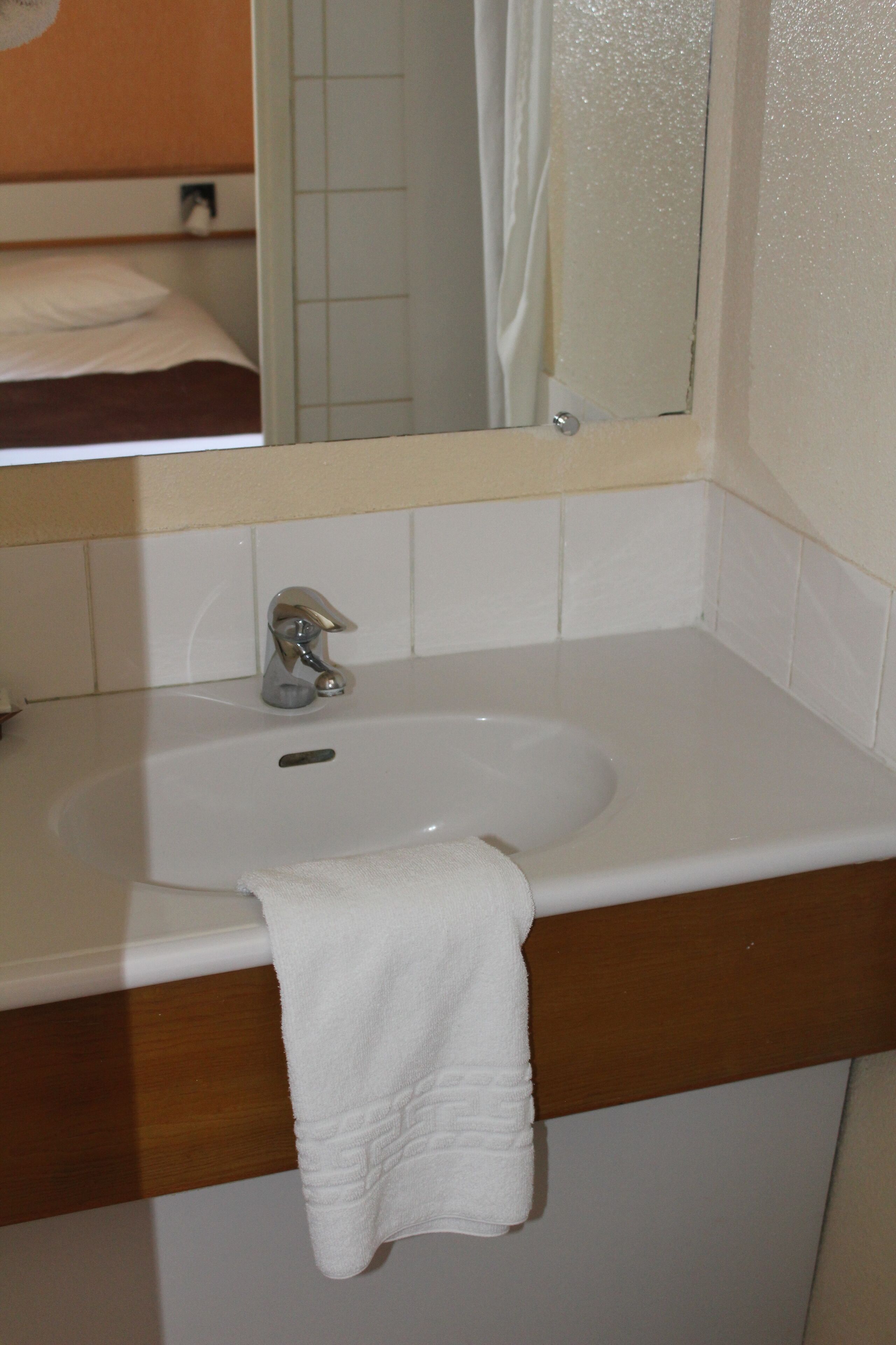 A bathroom with a white sink, a mirror, and a towel hanging on the side.