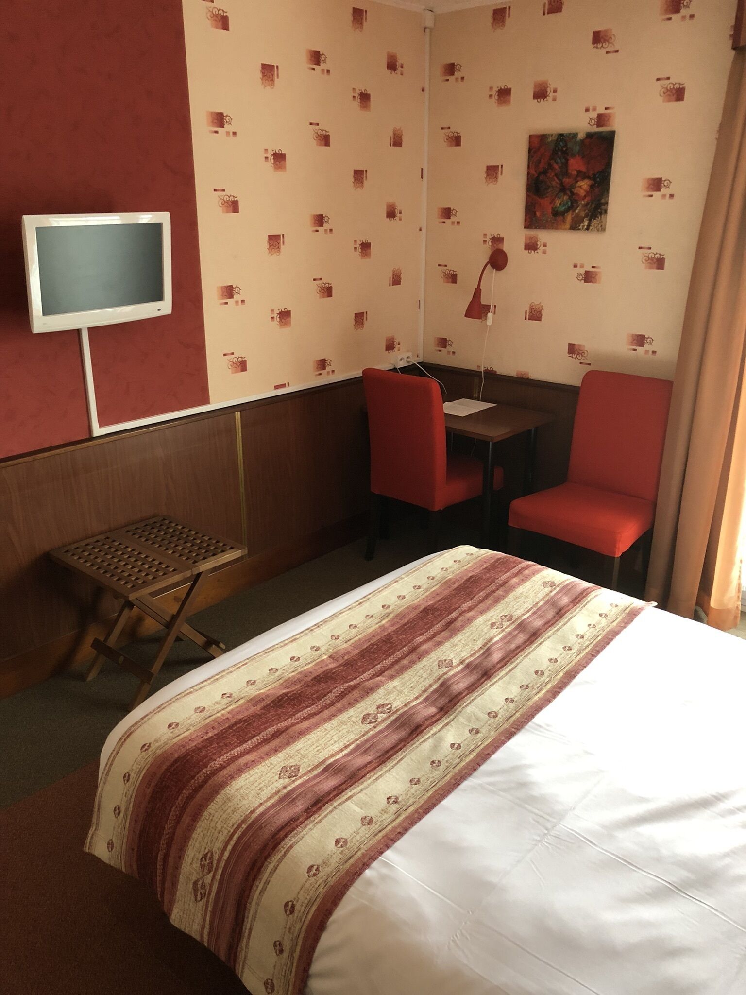A hotel room with a bed, a desk, two chairs, a television, and a small table.
