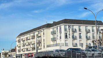A large hotel with multiple balconies and a green boat docked nearby.