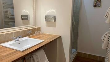 A bathroom with a white sink, a mirror, a towel rack, and a glass shower enclosure.