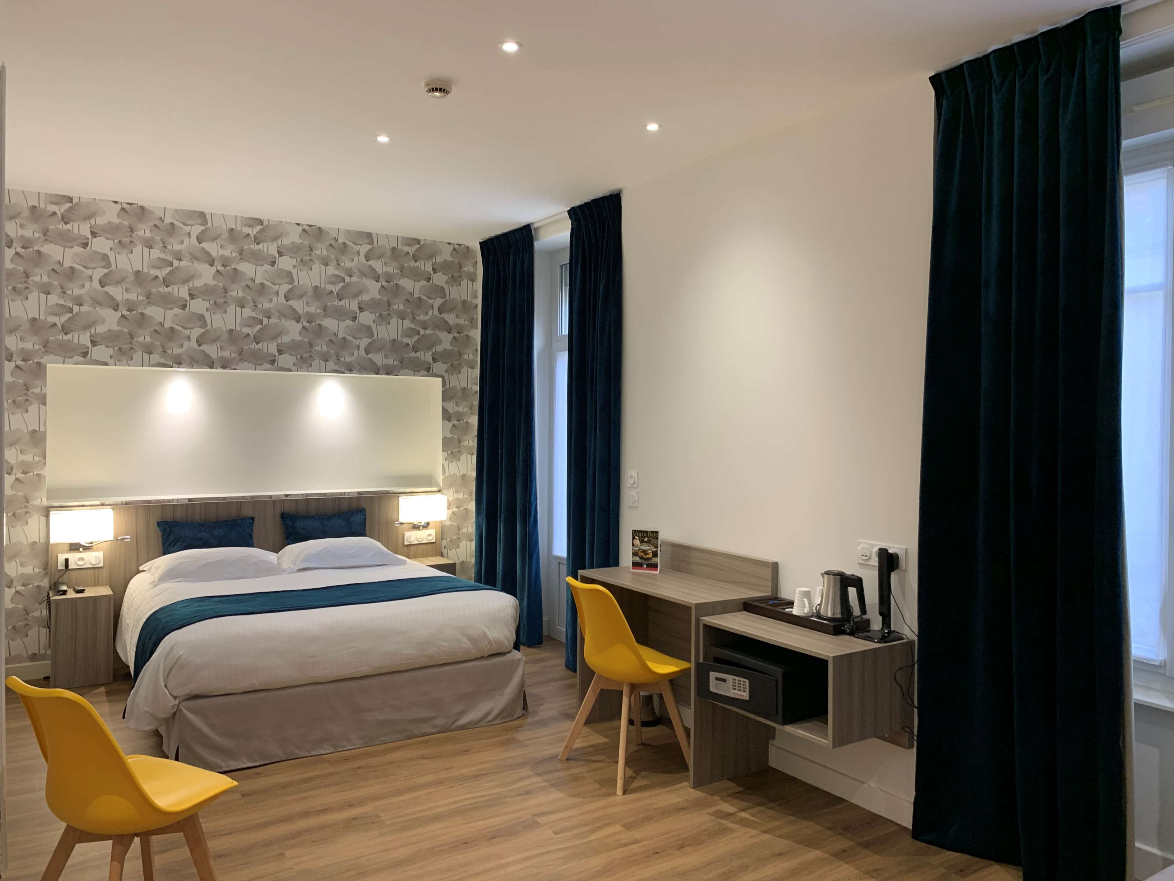Ein modernes Hotelzimmer mit einem großen Bett, einem Schreibtisch, zwei Stühlen und einer Wand mit Steinmuster.