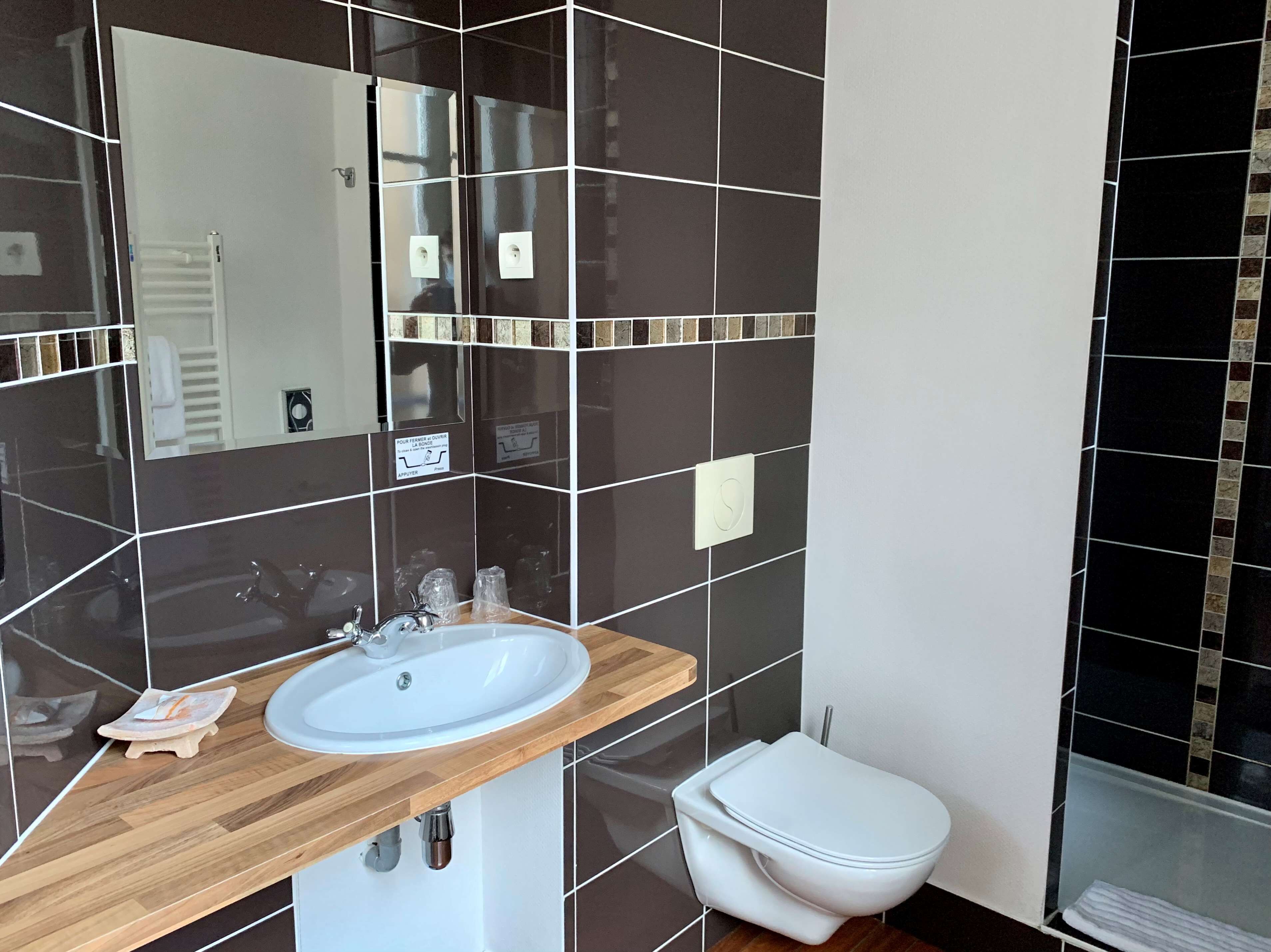 Un baño moderno con un espejo grande, un lavabo blanco y un inodoro.