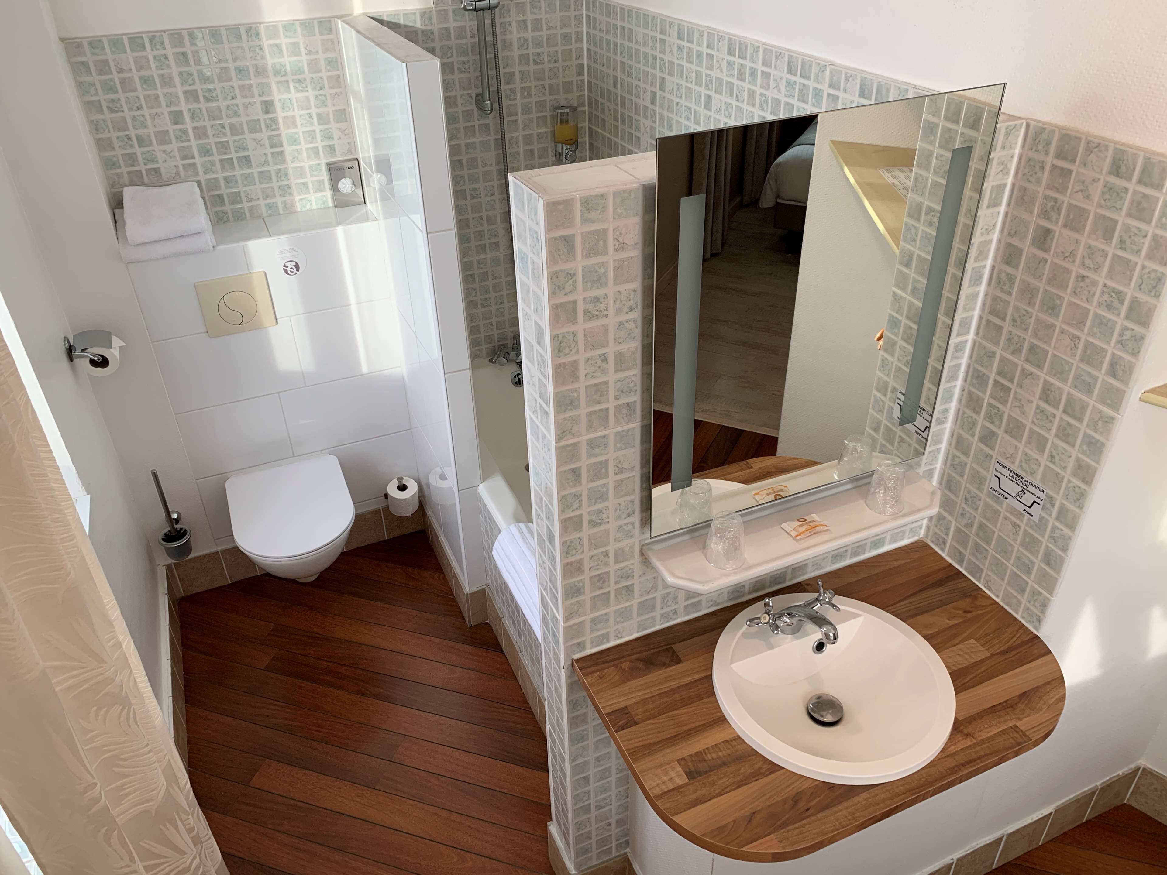 Un baño con un inodoro blanco, un tocador de madera con un lavabo y un espejo.