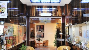 Eine Lobby mit Rattanmöbeln, Fliesenboden und Deckenleuchte in Blau.