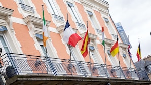 Ein Hotel mit mehreren Flaggen am Balkon, darunter die französische Flagge, und einem Schild, das es als Best Western Hotel kennzeichnet.