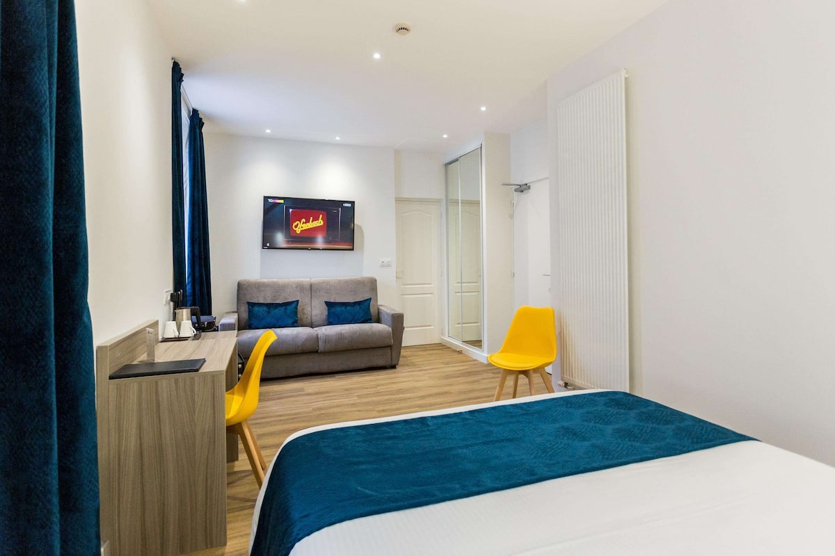 Una habitación de hotel moderna con cama, sofá, escritorio y televisor.