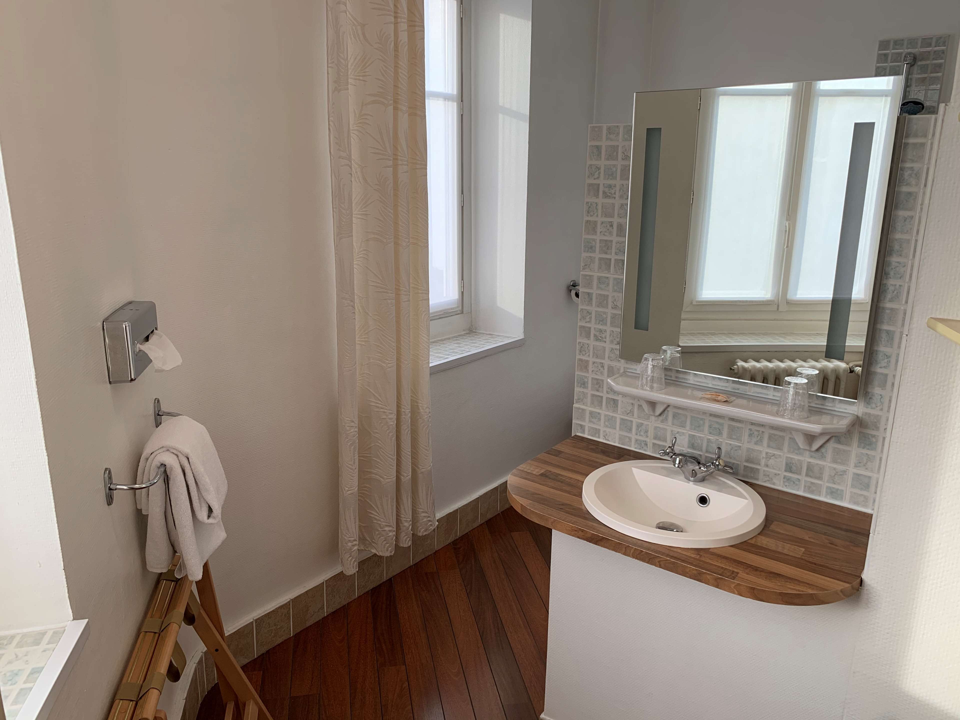 A bathroom with a wooden vanity, a white sink, a towel rack, a mirror, and a window with a view.