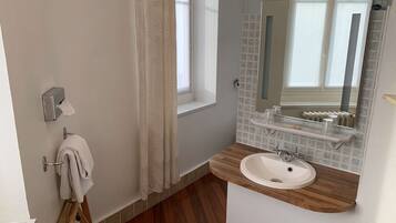 A bathroom with a wooden vanity, a white sink, a towel rack, a mirror, and a window with a view.