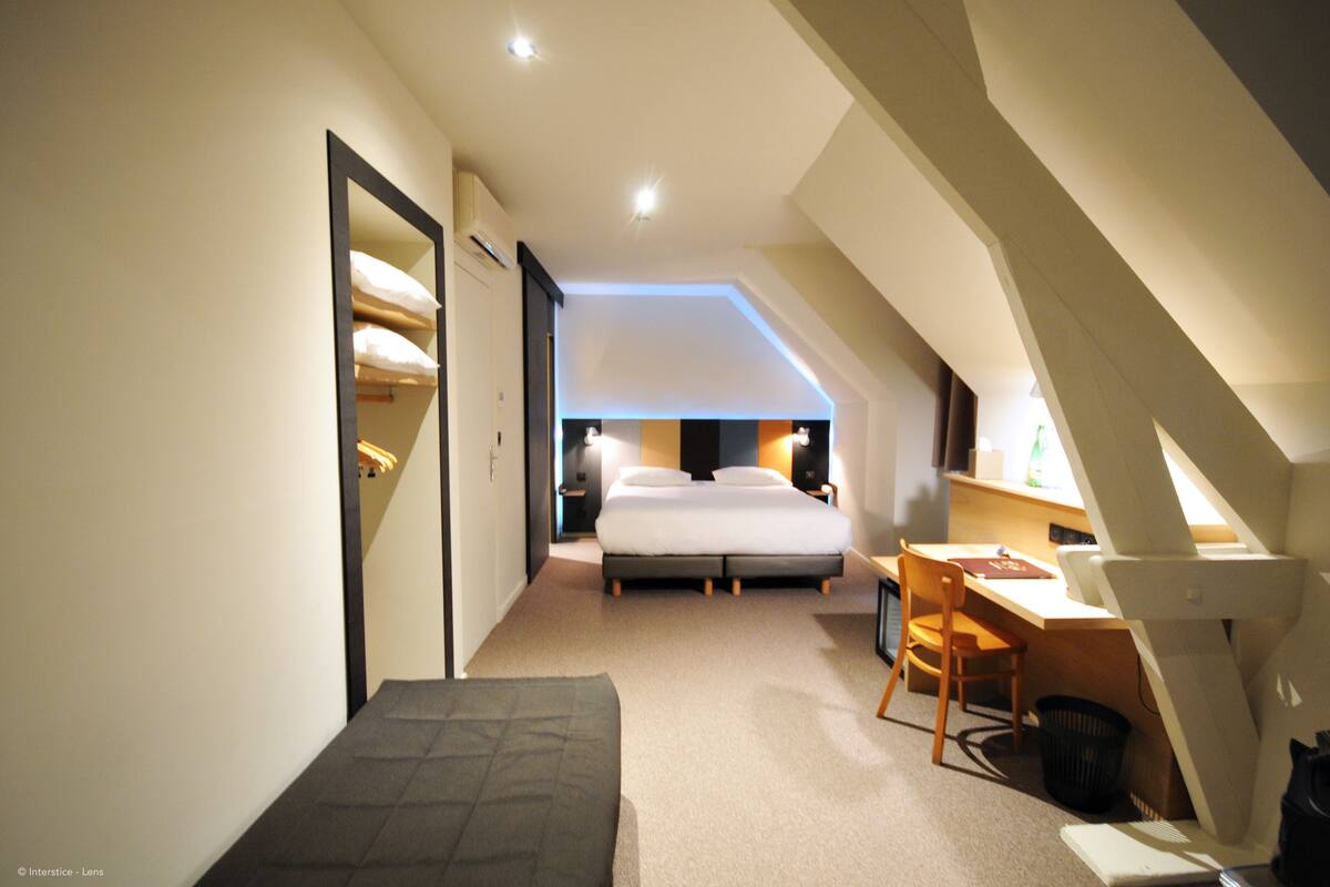 Ein kleines Hotelzimmer mit einem Bett, einem Schreibtisch und einem Stuhl.