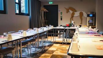 A conference room with long tables, chairs, and a large wall-mounted clock.