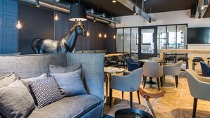 A modern interior with a sofa, chairs, a horse sculpture, and a bar area. - ibis Styles Laval Centre Gare (Laval)
