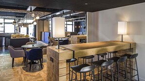 A modern bar area with a wooden counter, bar stools, and pendant lighting. - ibis Styles Laval Centre Gare (Laval)