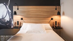 A modern hotel room with a wooden headboard, a large bed with white linens, and two bedside tables with lamps. - ibis Styles Laval Centre Gare (Laval)
