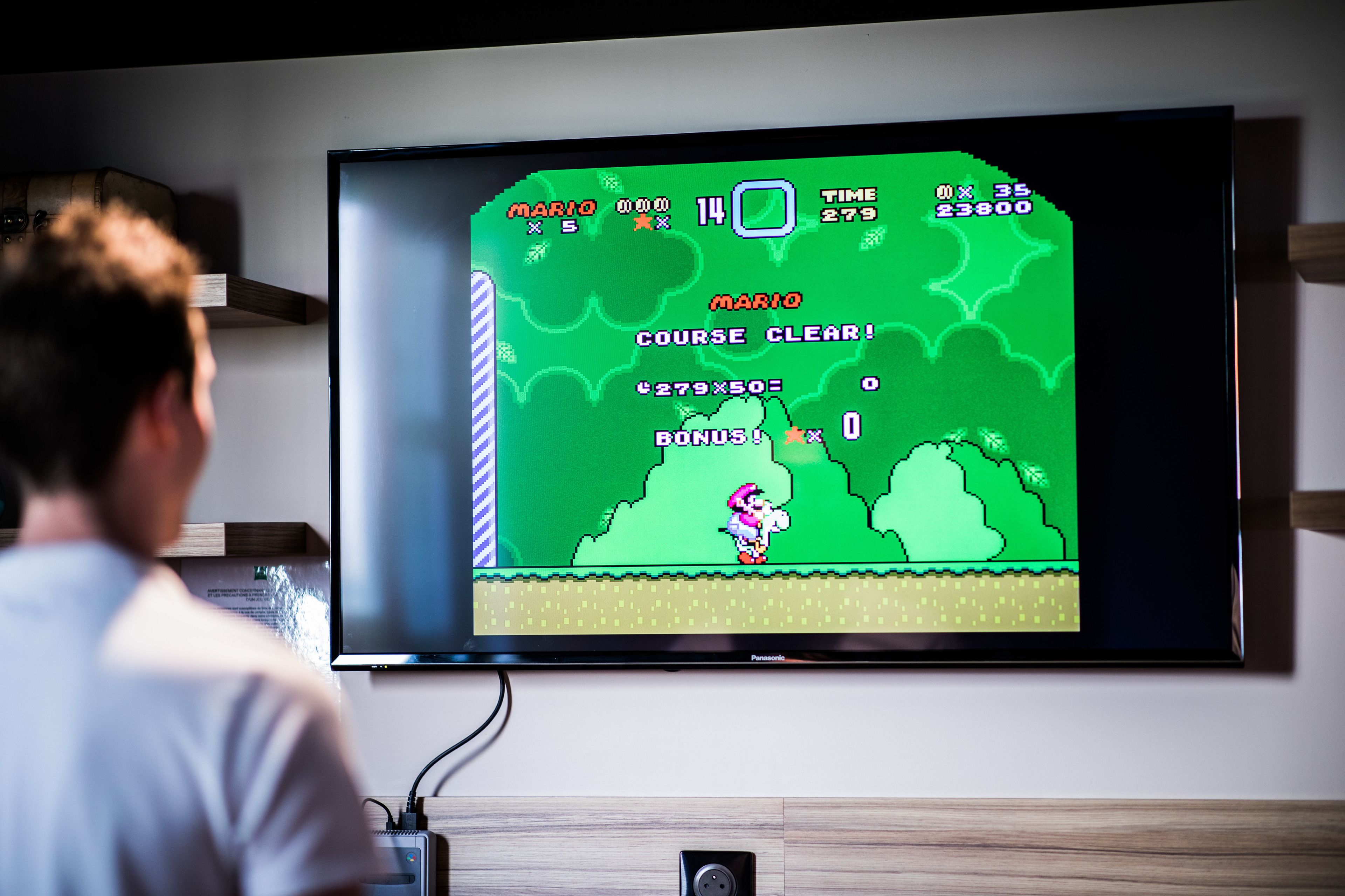 A person playing a video game on a large TV mounted on a wall.