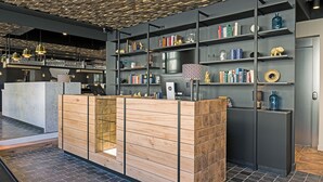 A reception area with a wooden counter, shelves with books and decorative items, and a bar area with glasses and bottles. - ibis Styles Laval Centre Gare (Laval)