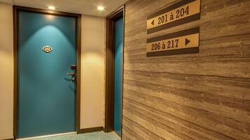A hotel corridor with a blue door labeled 202, and directional signs indicating room numbers 201 to 204 and 206 to 217.
