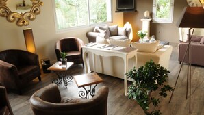 A living room with a sofa, armchair, coffee table, and a TV mounted on the wall. - Hôtel du Moulin, Niort (Niort)