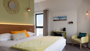 Ein Hotelzimmer mit einem großen Bett, einem Schreibtisch, einem Stuhl, einem Fenster mit Vorhängen und einem Bild an der Wand.