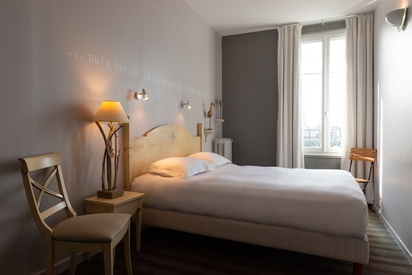 Un lit bien fait dans une chambre d’hôtel, avec vue sur la ville par la fenêtre.