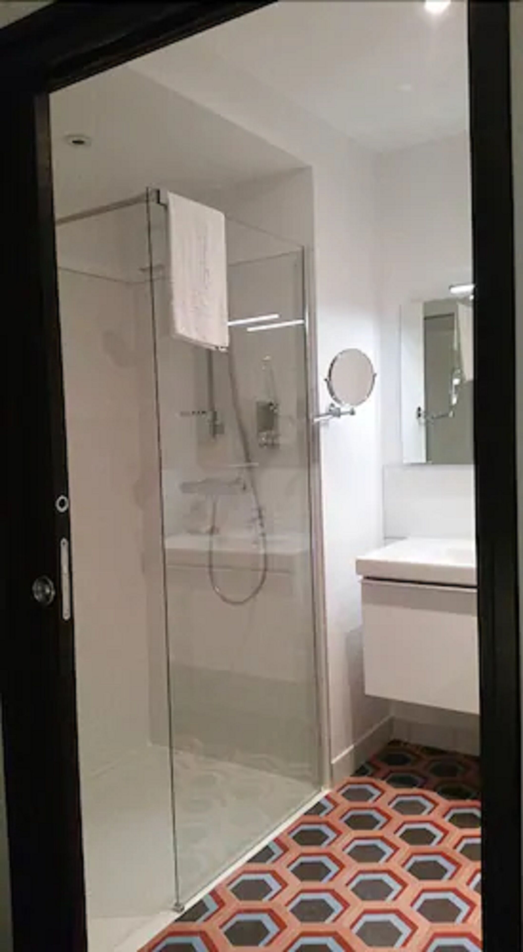 A modern bathroom with a glass-enclosed shower, a white sink, and a mirror.