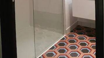 Une salle de bain moderne avec une douche à parois de verre, un lavabo blanc et un miroir.