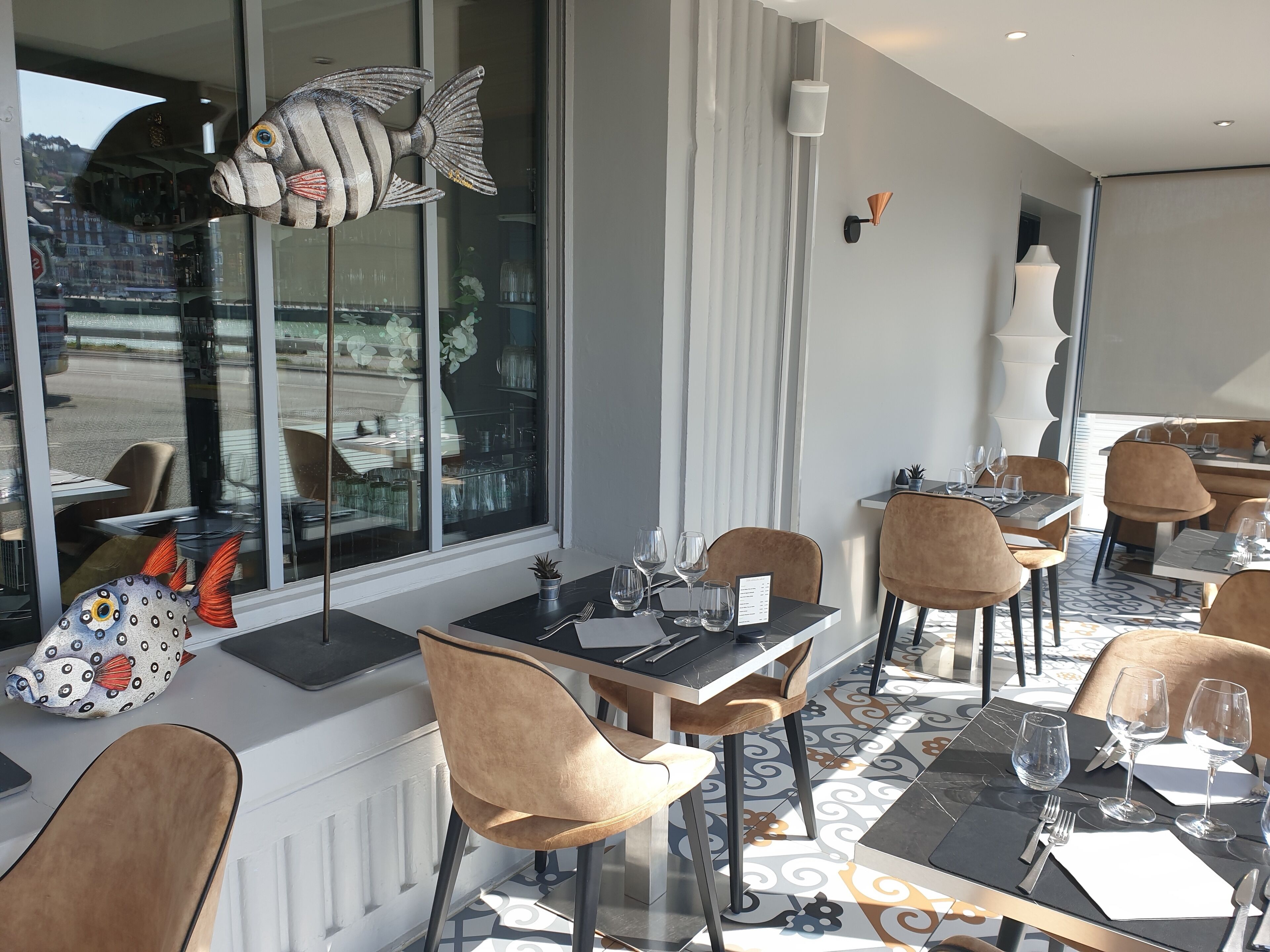 A restaurant with modern decor, featuring a large fish decoration, plush chairs, and a patterned floor.