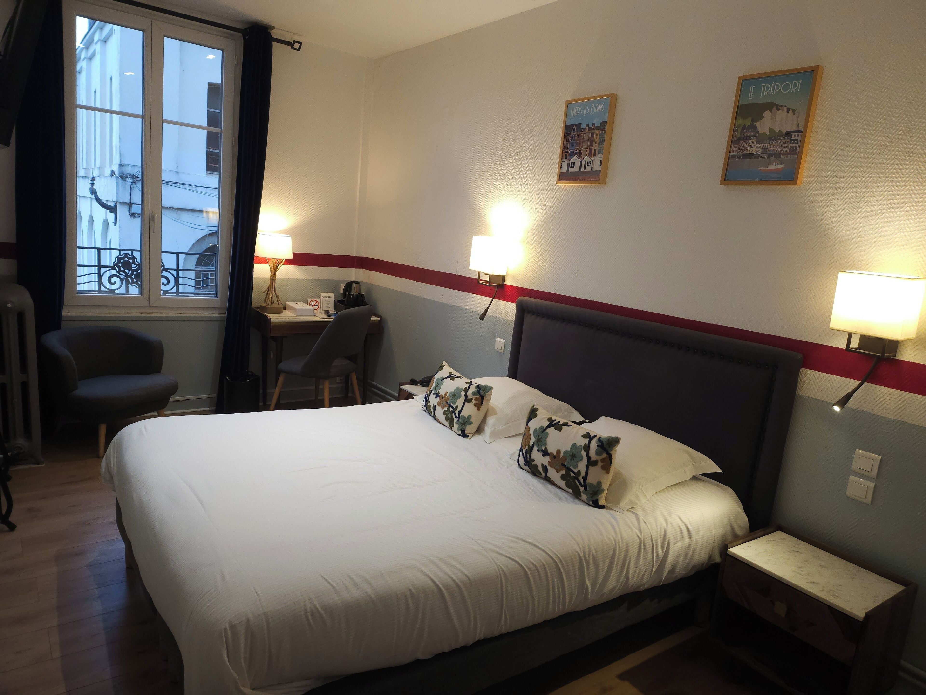 Une chambre d’hôtel avec un grand lit, un bureau, une chaise et une fenêtre avec des rideaux.