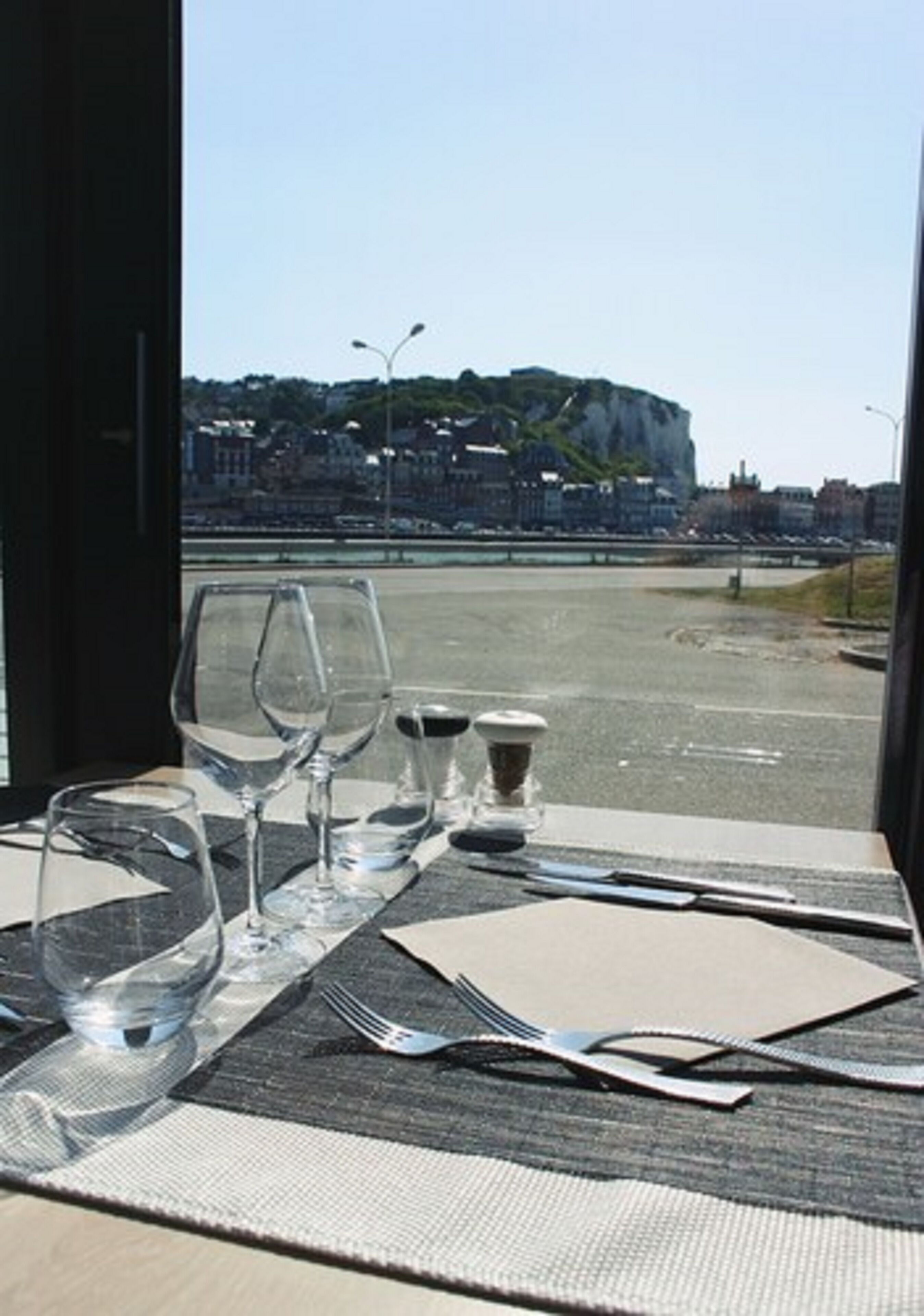 A table set for dining with a view of a cliff and cityscape.