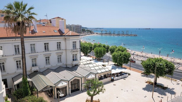 A hotel with a terrace, palm trees, and a view of the beach and sea. - Excelsior (Saint-Raphael)