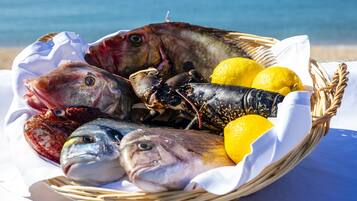 Una cesta de mariscos frescos, con pescado y langosta, sobre una mesa con vista al mar.