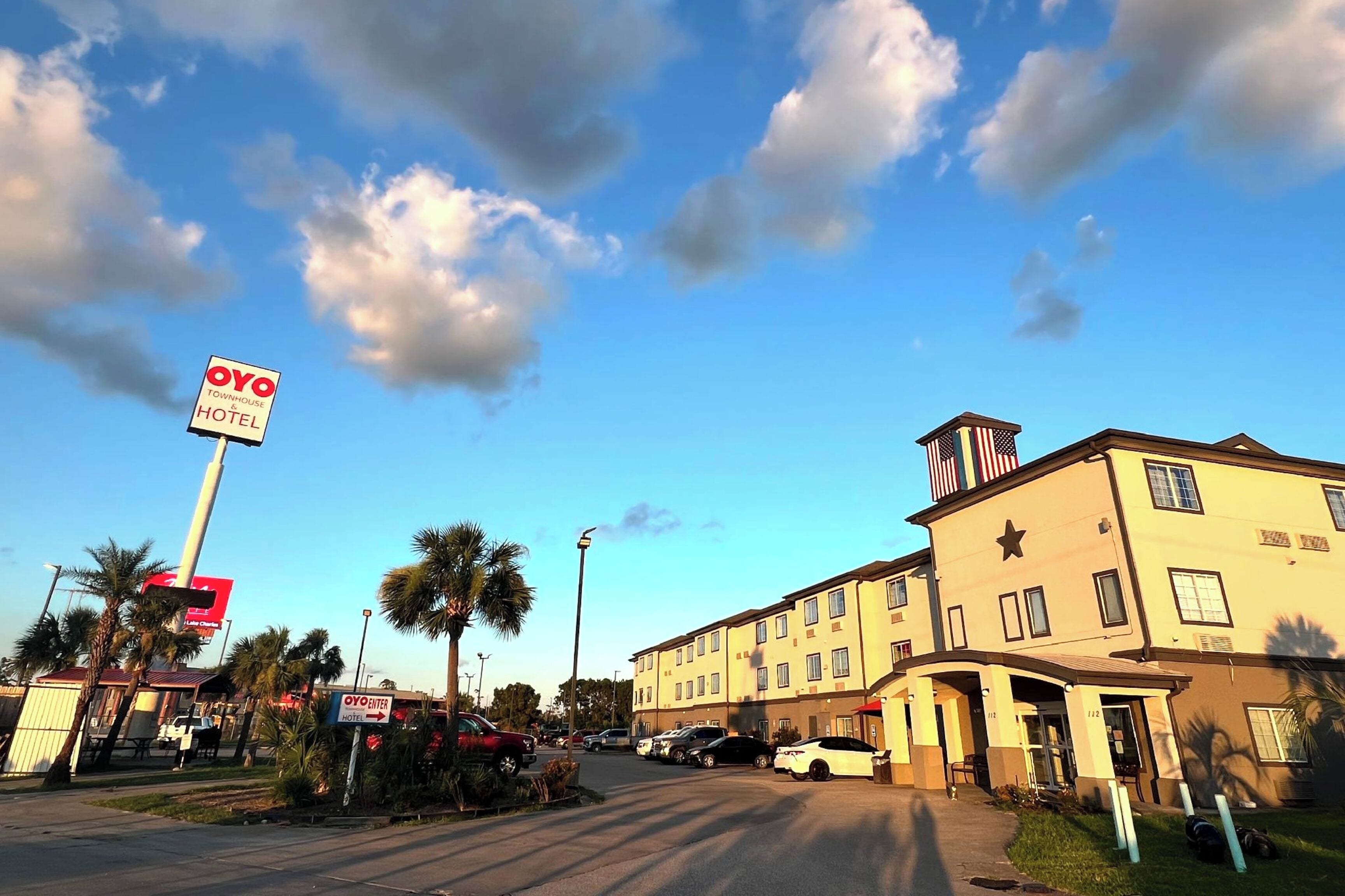 A hotel with a prominent sign, a parking lot, and a clear sky.