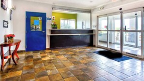 A reception area with a blue door, a reception desk, and a tiled floor. - Oyo Townhouse Sulphur,LA Extended Stay I-10 (Sulphur)