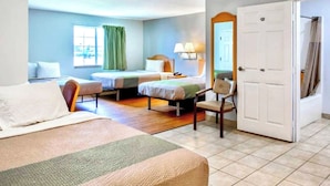 A hotel room with two beds, a chair, a desk, a lamp, and a door. - Oyo Townhouse Sulphur,LA Extended Stay I-10 (Sulphur)
