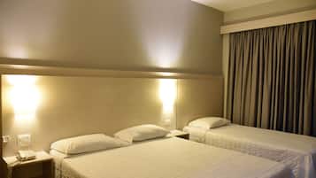 A hotel room with two beds, a nightstand with a phone, and a curtain.