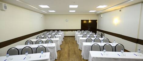 A conference room with rows of tables, chairs, and water bottles.