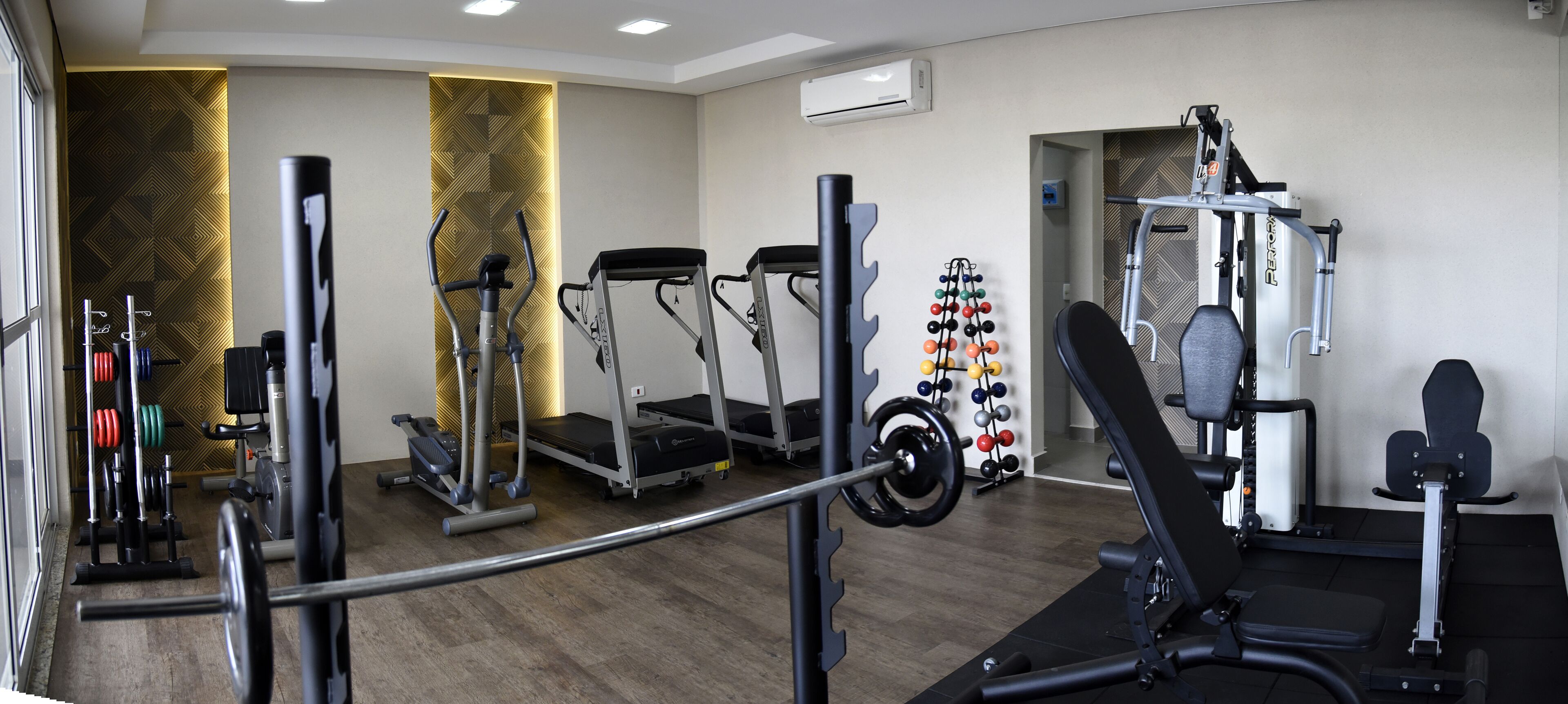 A gym with treadmills, elliptical machines, weight benches, and a variety of weights.