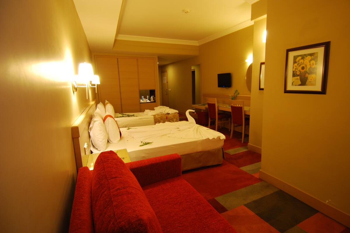 A hotel room with two beds, a desk, a chair, and a TV.