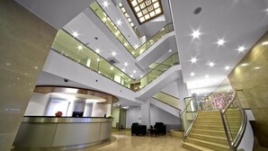 A modern hotel lobby with a central reception desk, multiple floors with glass railings, and a grand staircase. - SV Business Hotel Diyarbak ır (Diyarbakir)