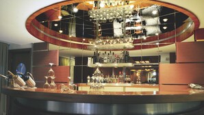 A bar area with a circular mirror reflecting the ceiling and lights, a variety of bottles and glasses on the counter, and a phone on the right side. - SV Business Hotel Diyarbakır (Diyarbakir)