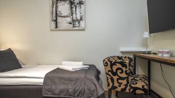 Una habitación de hotel con una cama, una silla, un escritorio, un televisor de pantalla plana y una obra de arte en la pared.